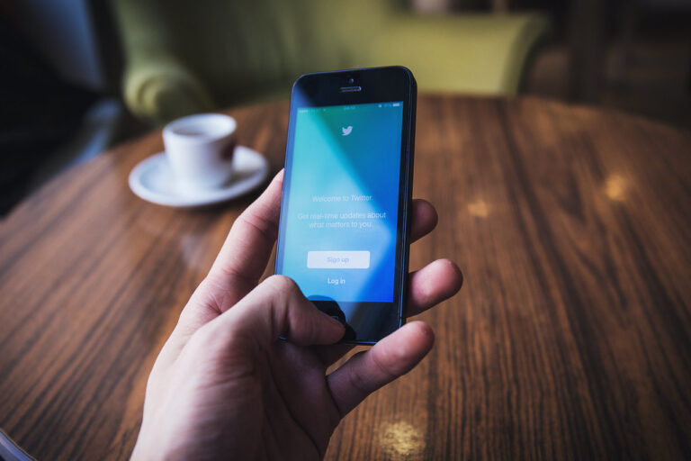 Ecran de smartphone affichant une interface de recherche d'application sociale, tenu en main dans un bureau lumineux