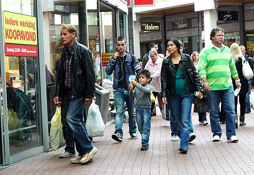 Rue commerçante animée avec des passants et des vitrines de magasins