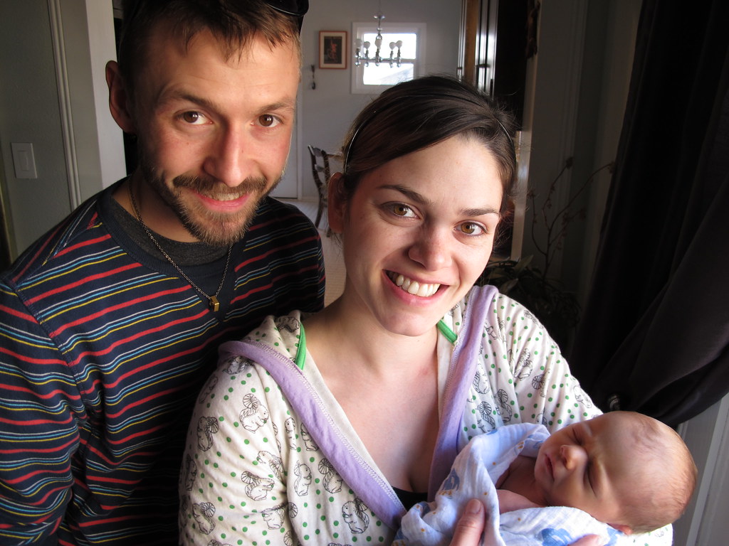 Jeune parent tenant un nouveau-né près d'une fenêtre à la maison