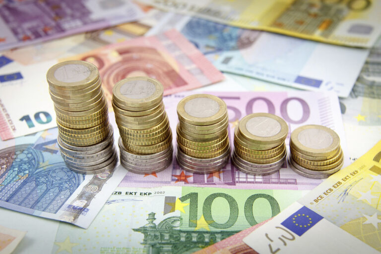 Des piles de pièces en euros décroissantes posées sur des billets en euros