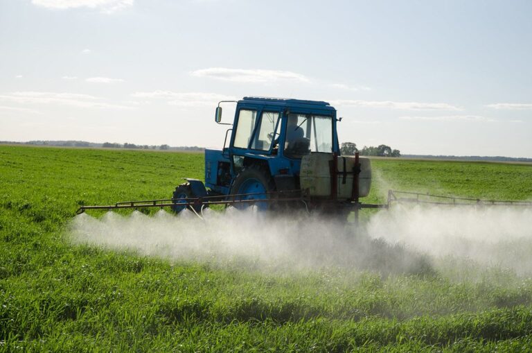Champ agricole français avec un tracteur épandant un traitement, ciel couvert au-dessus des cultures